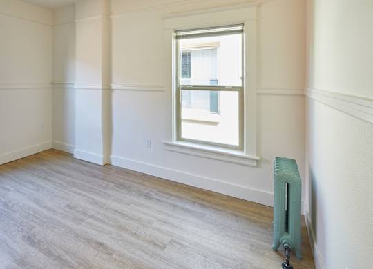 A room with a window and a radiator on the floor.