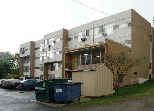 A large apartment building with a dumpster in front of it.