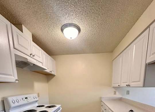 A kitchen with white cabinets and a stove top oven.