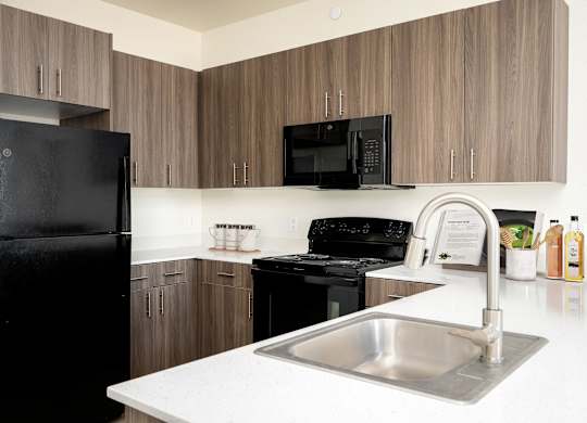 A kitchen with a black refrigerator and a black microwave.