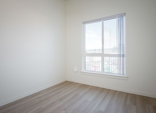A room with a window and wooden flooring.