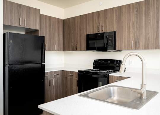 A kitchen with a black fridge, black microwave, and black stove.