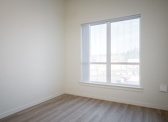 A room with a window and wooden flooring.