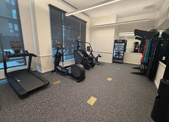 A gym with treadmills, elliptical machines, and a weight rack.