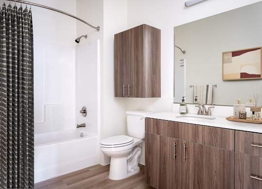 A modern bathroom with a white toilet and a wooden cabinet.