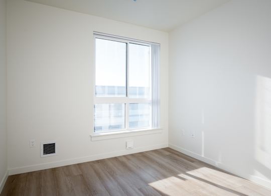 A room with a window and wooden flooring.