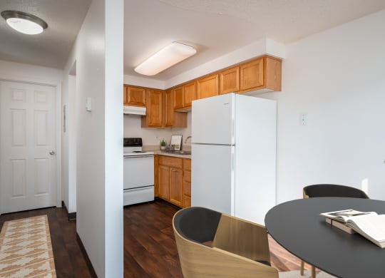 a kitchen with white appliances and wooden cabinets and a dining room table