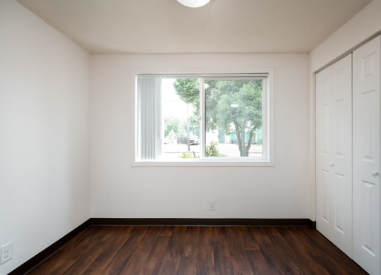 an empty room with a large window and wooden floors