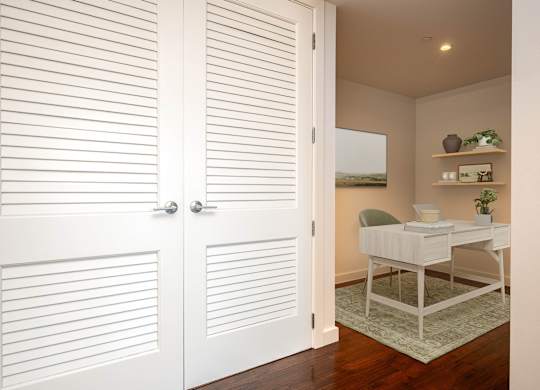 A white desk with a chair and a shelf with green plants.