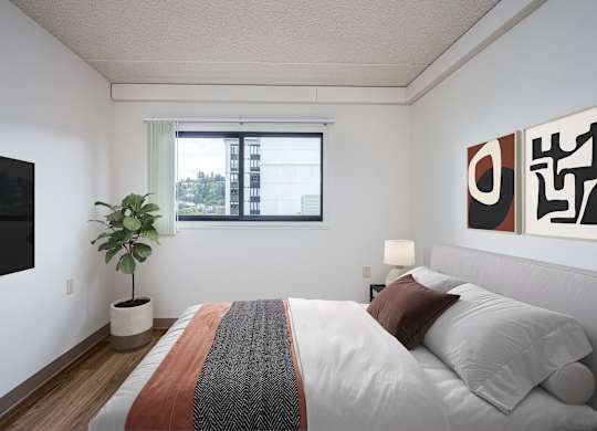 A bedroom with a bed, a potted plant, and a painting on the wall.