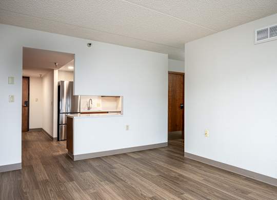 A room with white walls and wooden flooring with a door on the right.