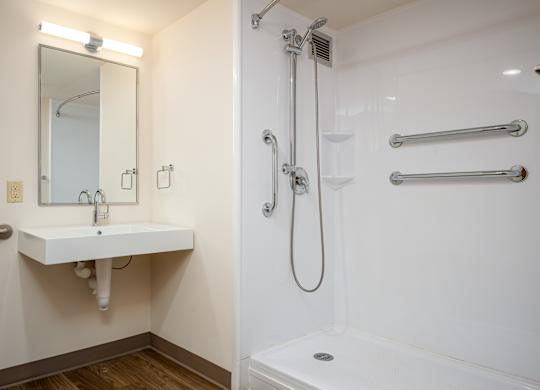 A white bathroom with a sink, mirror, and shower.