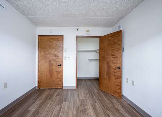 A room with two wooden doors and a white wall.