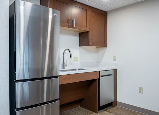 A kitchen with a stainless steel refrigerator and wooden cabinets.