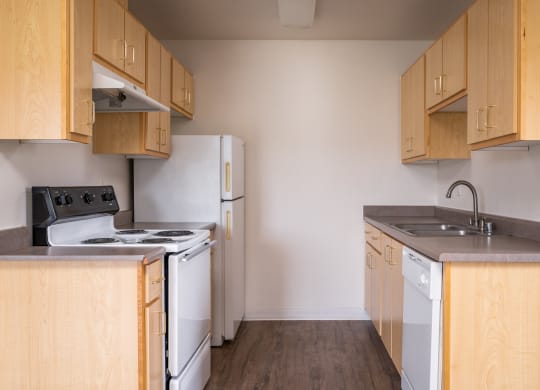 an empty kitchen with wood cabinets and white appliances