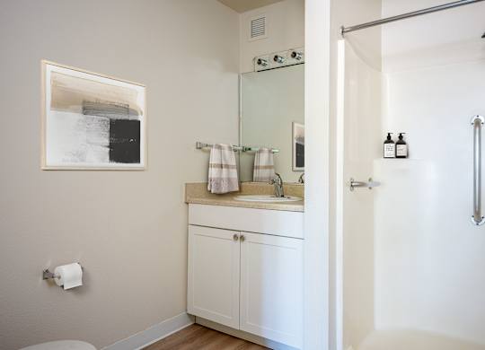 A white bathroom with a toilet, sink, and shower.