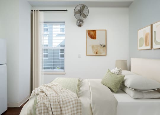 a bedroom with a bed and a fan on the wall