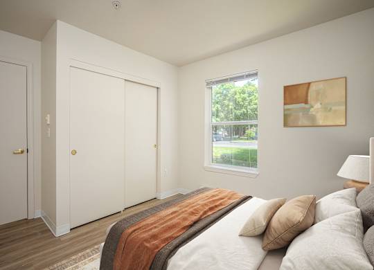 A bedroom with a bed, pillows, and a window.