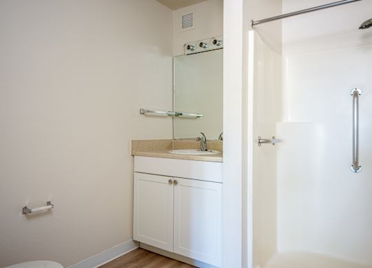 A white bathroom with a sink and a shower.