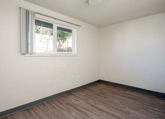 A room with a window and wooden flooring.