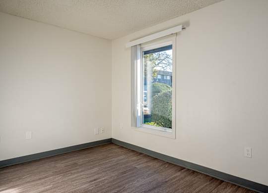 A room with a window and wooden flooring.