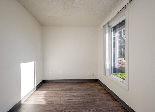 A room with a window and wooden floor.
