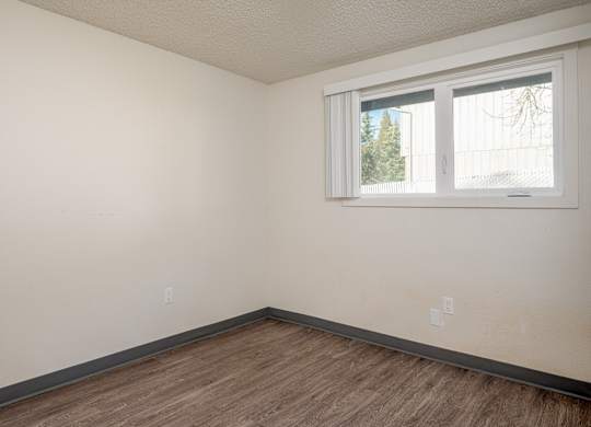 Empty room with a window and wooden floor.