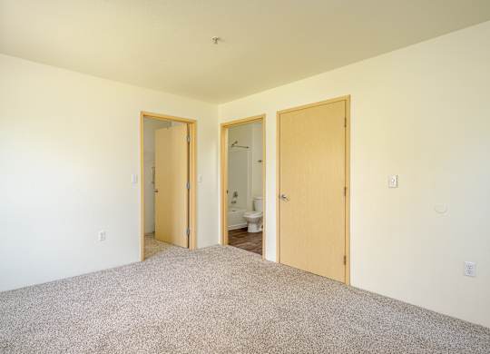 A room with a carpeted floor and three doors.