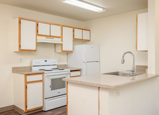 A kitchen with white appliances and wooden cabinets.