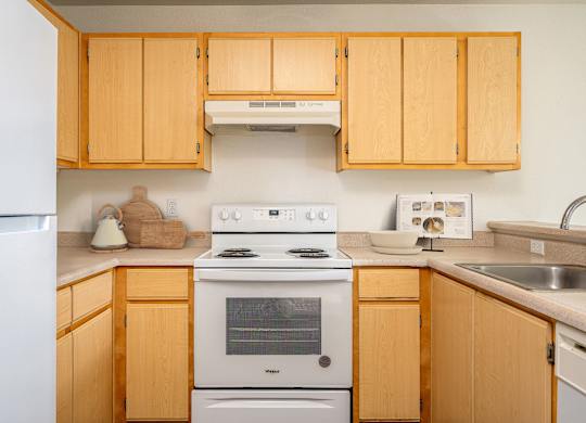 A kitchen with wooden cabinets and a white stove top oven.
