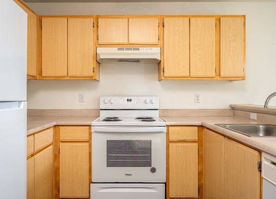 A kitchen with wooden cabinets and a white stove top oven.
