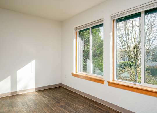 A room with a window and a wooden floor.