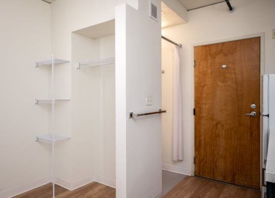 a walk in closet in a bedroom with a wooden door and white walls