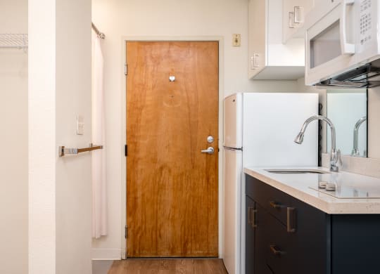 a kitchen in a small apartment with a wooden door and white appliances