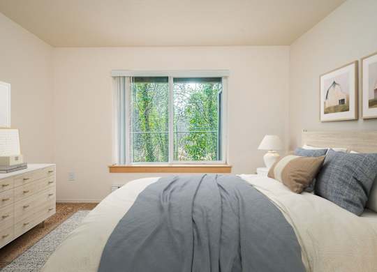 A bedroom with a large bed and a window with a view of trees.