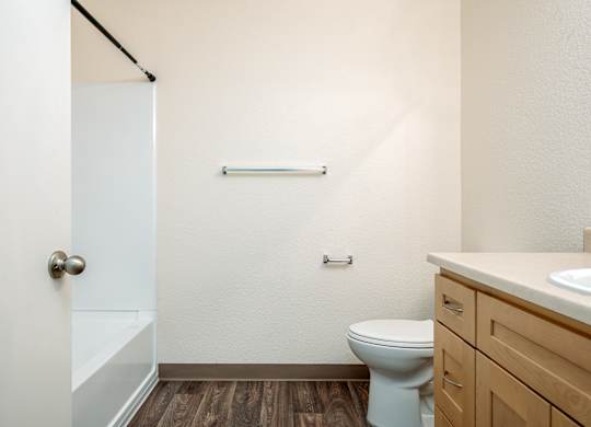 A white toilet sits in a bathroom with a white door and a white sink.