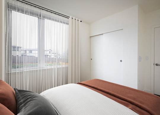 A bedroom with a large bed and a view of the city through the window.