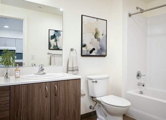 A white toilet sits in a bathroom next to a sink and a bathtub.