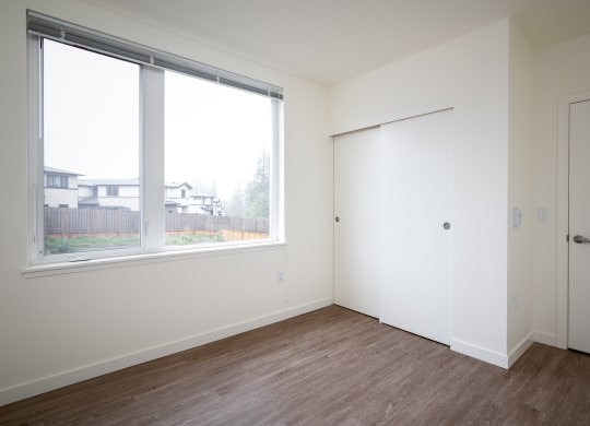 an empty bedroom with a large window and a door