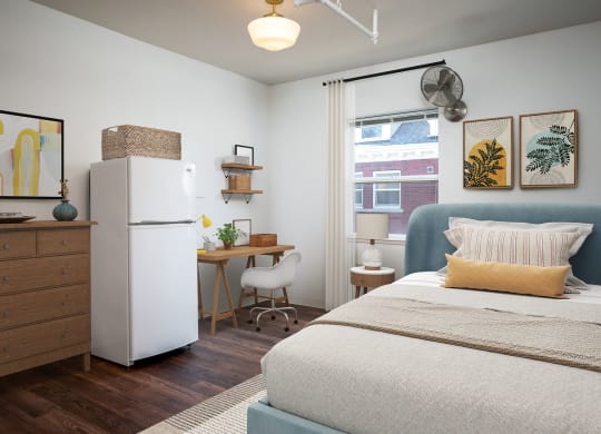 a bedroom with a bed and a refrigerator and a desk