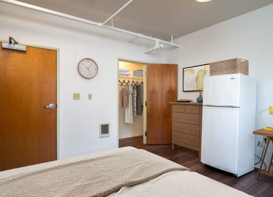 a bedroom with a bed and a refrigerator and a closet