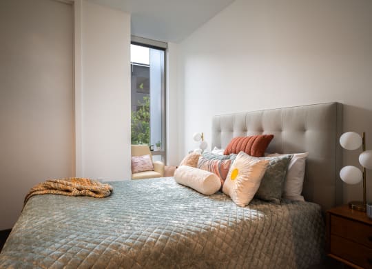 a bedroom with a bed and pillows and a window