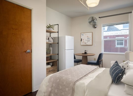 a bedroom with a bed and a refrigerator in the corner