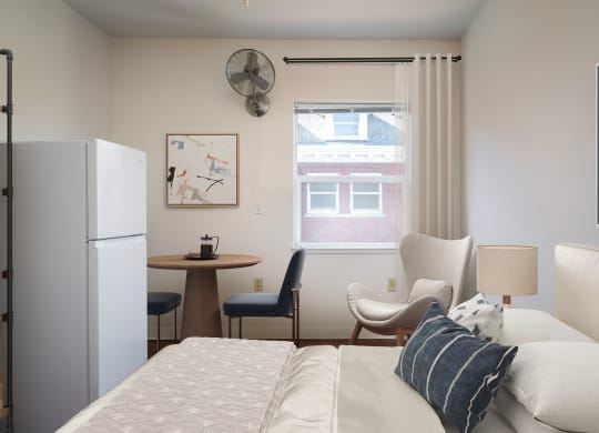 a bedroom with a bed and a refrigerator and a table with chairs