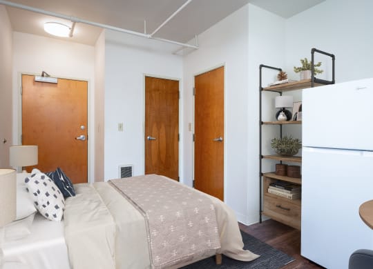 a small bedroom with a bed and a refrigerator