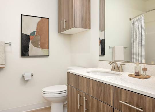 A bathroom with a toilet, sink, and a painting on the wall.