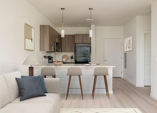 A modern kitchen with a white couch and wooden bar stools.