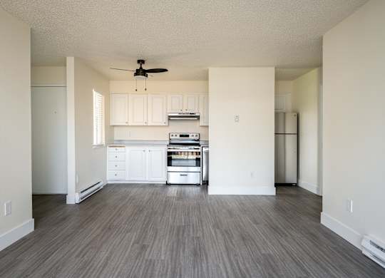 A spacious kitchen with white cabinets and a wood floor.