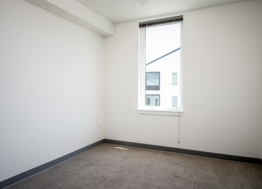 an empty room with a window and a carpet