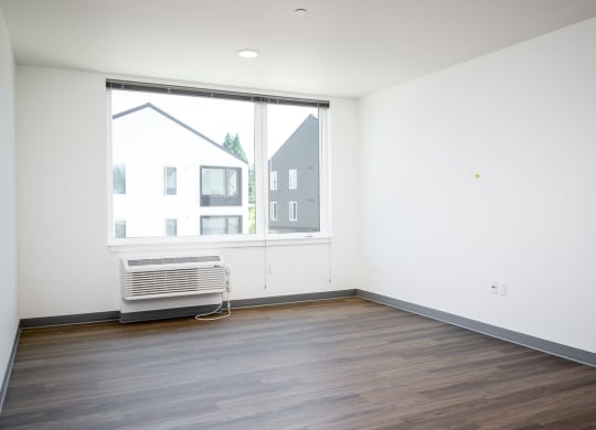 an empty living room with a large window and wooden floors